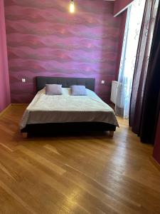 a bedroom with a bed and a pink wall at Central Park Apartment in Tbilisi City
