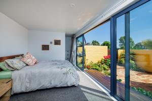 a bedroom with a bed and a large window at Viva Vida View - Paihia Holiday Home in Paihia