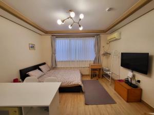 a small room with a bed and a television at There Bengdi in Jeju