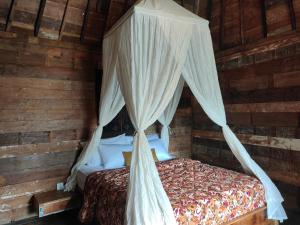 a bed with a canopy in a wooden room at Taruchi 4 bedrooms villa in Kesiman