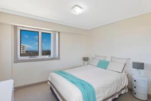 a white bedroom with a bed and a window at Sandy Cove Apartment The Entrance 29 in The Entrance +8 photos