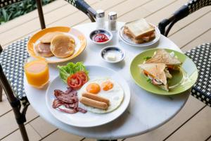 a white table with plates of breakfast foods and orange juice at Penpark Place in Bangkok