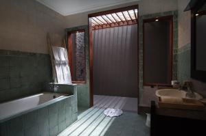 a bathroom with a bath tub and a sink at The Tukad Villa in Seminyak +27 photos