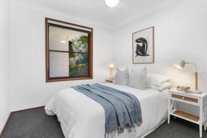 a white bedroom with a bed and a window at Sea Change in Shoal Bay