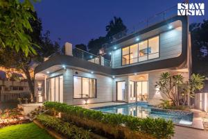 a house with a swimming pool at night at Cashew Creek by VEO - Part of StayVista with Pool & WiFi in Alibaug