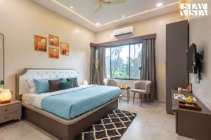 a bedroom with a bed and a tv in a room at Cashew Creek by VEO - Part of StayVista with Pool & WiFi in Alibaug +37 photos