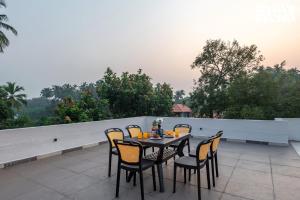 a table and chairs sitting on a patio at Cashew Creek by VEO - Part of StayVista with Pool & WiFi in Alibaug