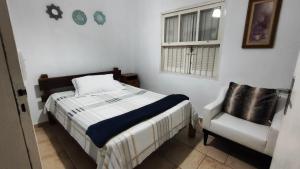 une chambre avec un lit, une chaise et une fenêtre dans l'établissement Casa com Piscina 200 m da Praia - São Sebastião, à São Sebastião 31 autres photos