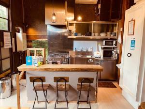 a kitchen with a counter and two stools in it at Aomori Kurahaku 青森蔵泊 in Kuroishi