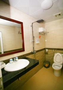 ein Badezimmer mit einem Waschbecken, einem WC und einem Spiegel in der Unterkunft Bao An Hotel in Diện Biên Phủ