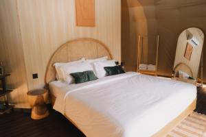 a bedroom with a large white bed with green pillows at RINDANG Glamping in Tlekung