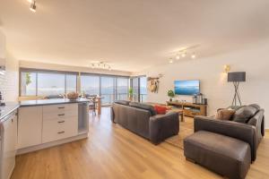 a living room with two couches and a kitchen at Boondelbah 4, 29 Soldiers Point Rd - waterfront bliss in Soldiers Point