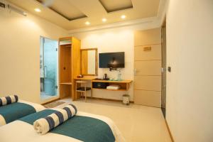 a bedroom with two beds and a desk with a television at Wish Guesthouse in Huraa