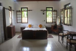 a bedroom with a bed in a room with windows at Rohini Heritage Bungalow in Ambalangoda