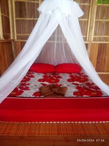 a red bed with red pillows and a mosquito net at Adefiro homestay in Waisai +54 photos