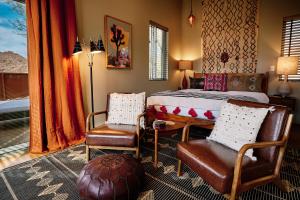 a bedroom with a bed and two chairs in it at Sacred Sands - Lobo Luna in Joshua Tree