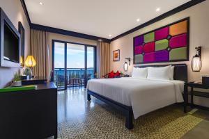 a bedroom with a large white bed and a television at Wyndham Garden Hoi An Cua Dai Beach in Hoi An