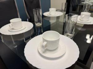 a table with white cups and plates and glasses at Zinnia North Tower 3202 in Manila