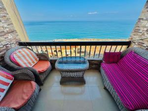 a balcony with two chairs and a table and the ocean at ALEX HOMES - Stanley Cozy Apartments with Direct Sea View in Alexandria