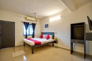 Un dormitorio con una cama con almohadas rosas y un televisor. en Baga beach see side in, en Calangute