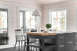 a kitchen with a table and chairs and windows at Villa Länsihuippu in Himos