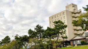 un alto edificio bianco con alberi di fronte di Okazaki Daiichi Hotel a Okazaki