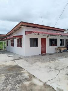 a white building with a red door in a parking lot at Roomstay Mok House - Unit 2 in Kuala Terengganu