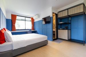 a bedroom with blue walls and a bed and a tv at Penpark Place in Bangkok