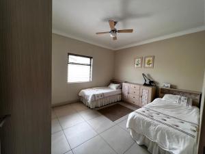 ein Schlafzimmer mit zwei Betten und einem Deckenventilator in der Unterkunft Leadwood Flat in Mondesa