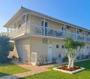 a large white house with a balcony and a palm tree at Elleana south Corfu in Agios Georgios