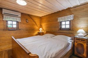a bed in a wooden room with two windows at Vineyard Cottage Skatlar in Otočec +29 photos