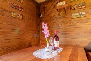 a bottle of wine and a vase of flowers on a table at Vineyard Cottage Skatlar in Otočec