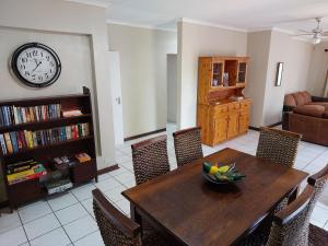 a dining room with a table and a clock on the wall at The Green Lizard Self-catering House in Nelspruit