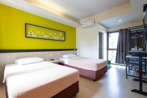 two beds in a room with a green wall at Penpark Place in Bangkok
