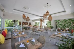 a restaurant with tables and chairs and windows at Tapa Tepi Kali Canggu in Canggu