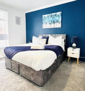 a bedroom with a large bed with a blue wall at Orchard Road in Portsmouth