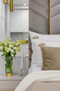 a vase of flowers on a table next to a bed at DOKI Living & Foodhall by Downtown Apartments in Gdańsk