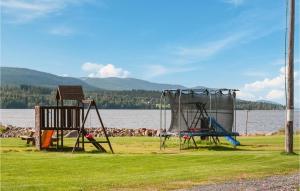 two playground equipment on the grass near a body of water at Gorgeous Home In Søre Osen With Wifi in Tørberget