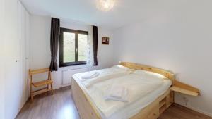 1 dormitorio con 1 cama con cabecero de madera y ventana en Apartment Piz Argient, en Samedan