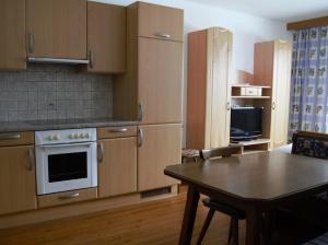 kuchnia z drewnianymi szafkami, stołem i telewizorem w obiekcie Appartment Danterhof w Mayrhofen