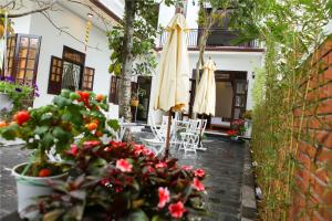 a patio with an umbrella and chairs and flowers at Blue Lake Homestay in Hoi An