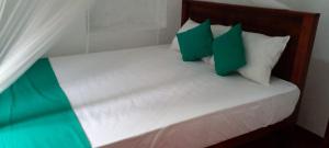 ein Bett mit grünen und weißen Kissen darauf in der Unterkunft Shine View in Dikwella + 8 Fotos