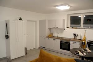 a kitchen with white cabinets and a table in it at TuaCasa - Gemütliches Souterrain Apartment in Lippstadt