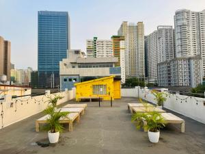 a rooftop with tables and benches on a city skyline at Cheese Hostel Manila in Manila