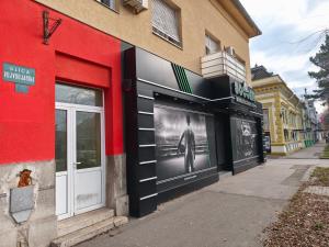 a red building with a black and white photo on it at Apartmani Trastevere Sombor in Sombor