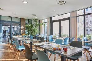 a restaurant with tables and chairs and windows at Appart'hôtel Odalys City - Bioparc Lyon Est in Lyon +61 photos