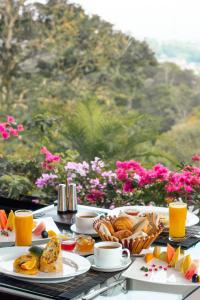 a table topped with plates of food and orange juice at The Theva Residency in Kandy