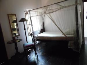a bedroom with a canopy bed and a chair at The Dream House in Unawatuna