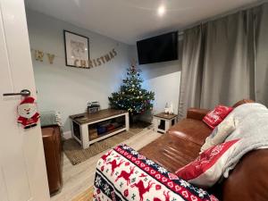a living room with a christmas tree and a couch at Orchard Lodge -Coastal Retreat, new build, village views, private garden and terrace in Saint Brides Major