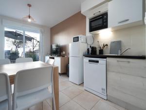 a kitchen with white appliances and a table with chairs at La Dune N 59 - Villa 3P6 in Sérignan